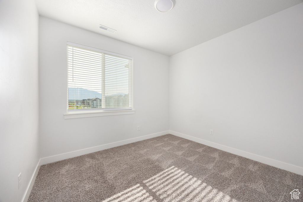 Carpeted spare room featuring baseboards