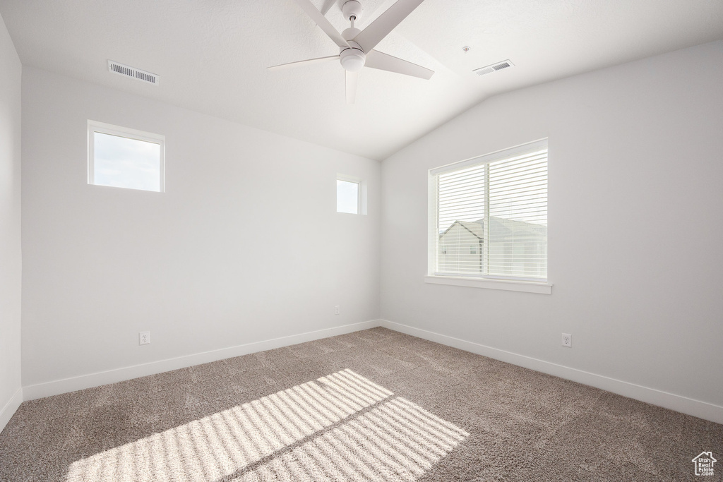 Unfurnished room featuring light carpet, plenty of natural light, lofted ceiling, and ceiling fan