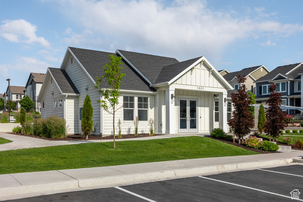 View of front of property featuring french doors, board and batten siding, uncovered parking, and a residential view