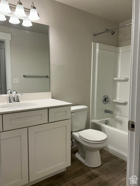 Bathroom featuring wood finished floors, vanity, toilet, and shower / tub combination