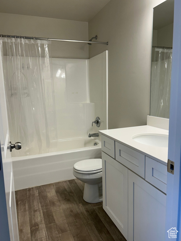 Bathroom with wood finished floors, vanity, shower / bath combo, and toilet