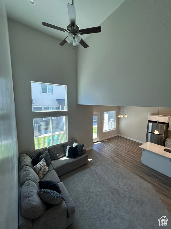 Living area featuring a high ceiling, baseboards, wood finished floors, and a ceiling fan