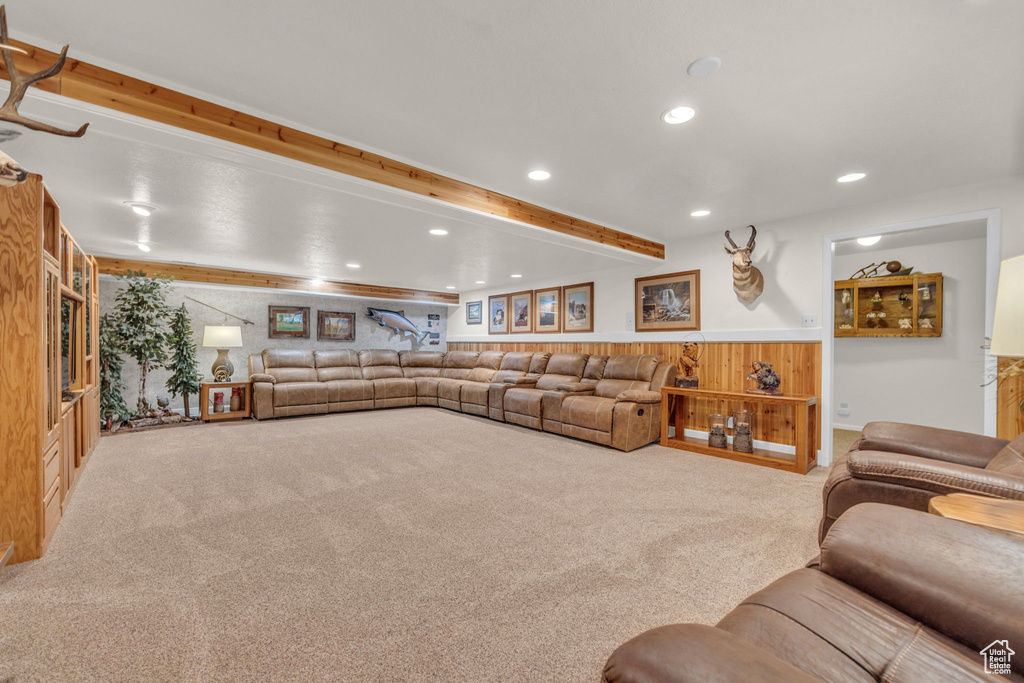 Carpeted living room with recessed lighting, beam ceiling, wainscoting, and wooden walls