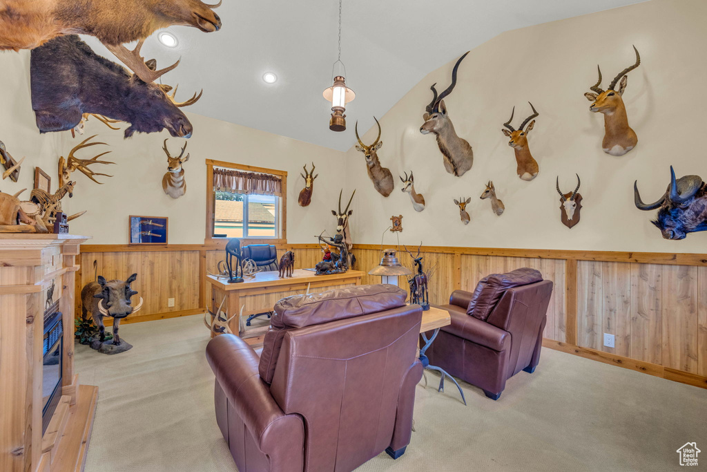Carpeted living room featuring a wainscoted wall, vaulted ceiling, a high end fireplace, wood walls, and recessed lighting