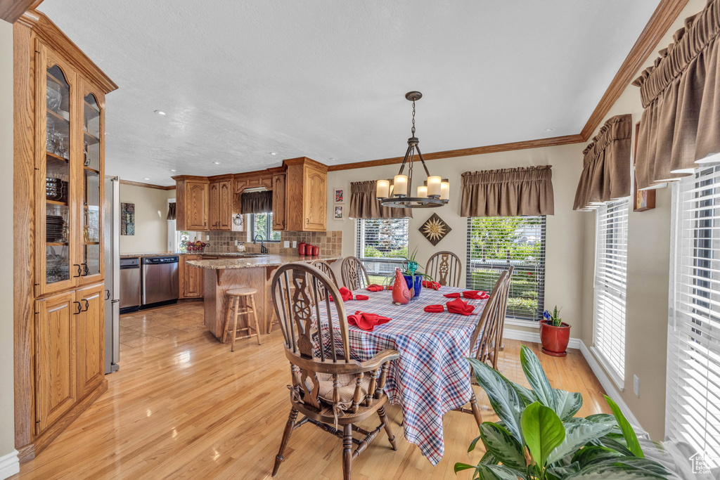 Dining room featuring light wood-style flooring, plenty of natural light, crown molding, a chandelier, and recessed lighting