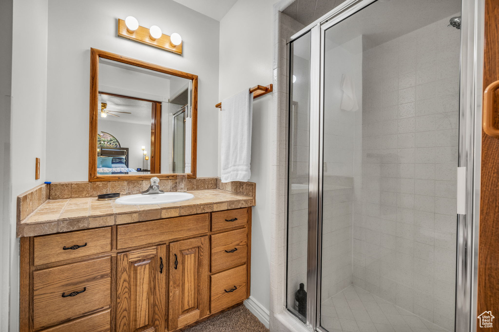 Bathroom with vanity, a shower stall, and ceiling fan