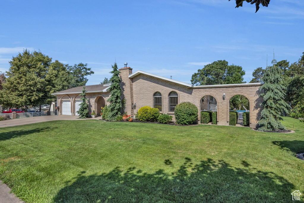 View of front of property featuring a front yard, concrete driveway, brick siding, and a garage