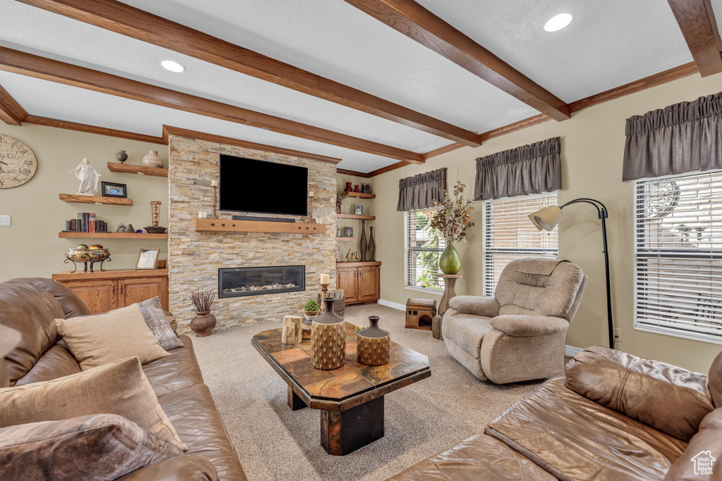 Carpeted living area with beam ceiling, crown molding, a stone fireplace, baseboards, and recessed lighting