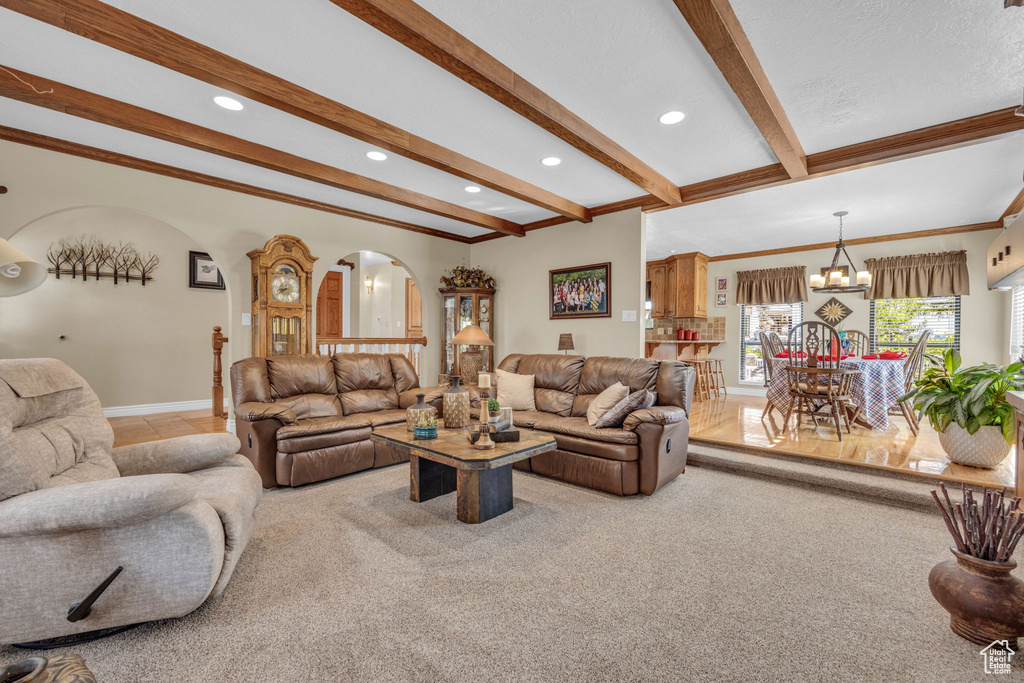 Living area featuring arched walkways, beamed ceiling, a chandelier, recessed lighting, and crown molding