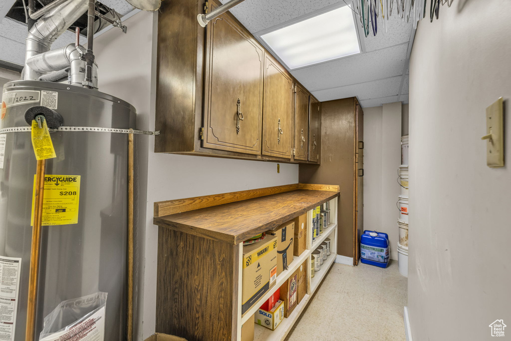 Basement with water heater, light floors, and baseboards