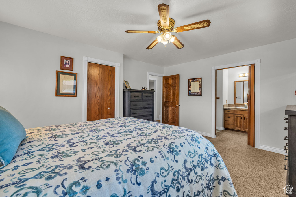 Carpeted bedroom with baseboards, a closet, ceiling fan, and ensuite bathroom