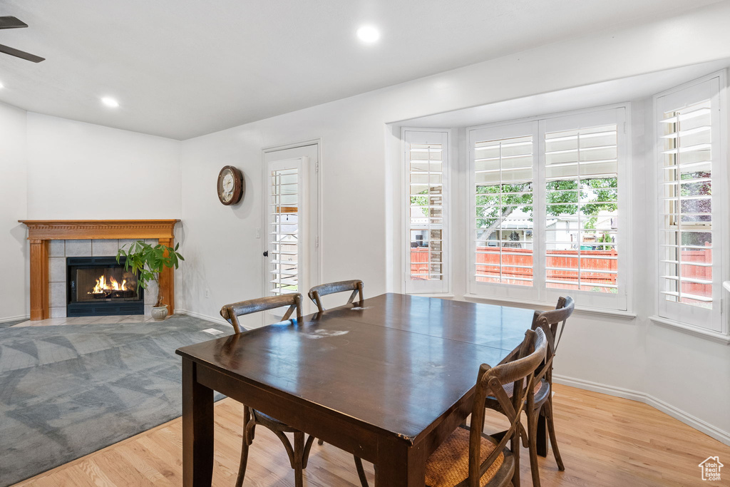 Dining room featuring healthy amount of natural light, light wood-style flooring, a tiled fireplace, recessed lighting, and ceiling fan