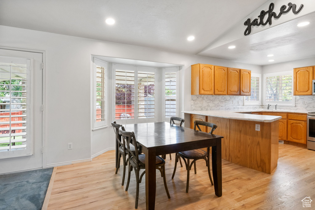 Dining room with light wood finished floors, recessed lighting, and lofted ceiling