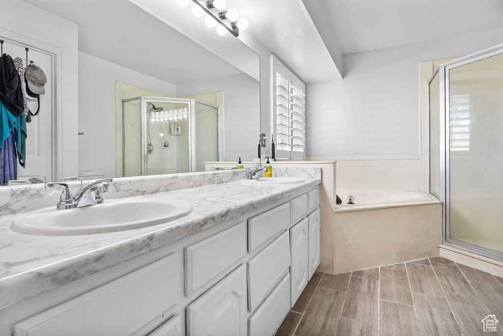 Bathroom with a stall shower, double vanity, a garden tub, and wood finish floors