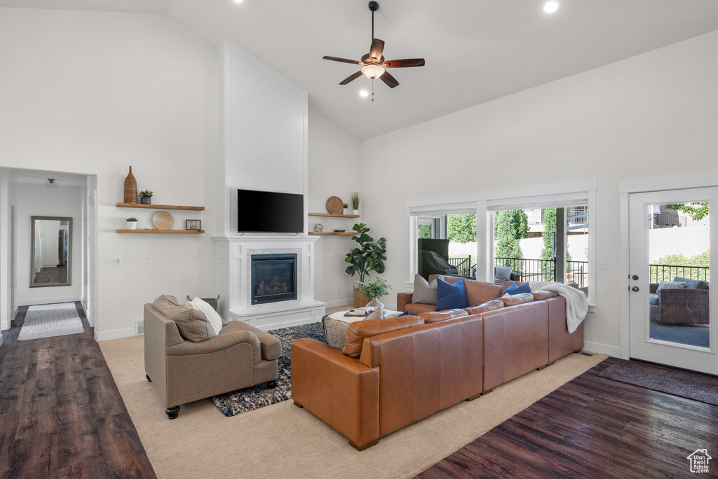 Living area featuring high vaulted ceiling, a glass covered fireplace, wood finished floors, ceiling fan, and recessed lighting