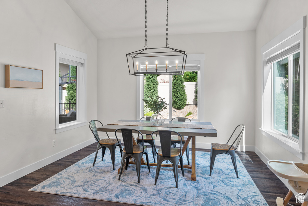 Dining area with a chandelier and dark wood-style flooring