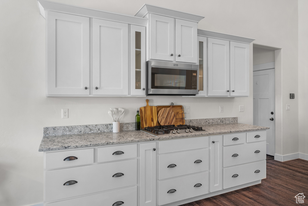 Kitchen featuring appliances with stainless steel finishes, white cabinets, glass insert cabinets, and dark wood finished floors