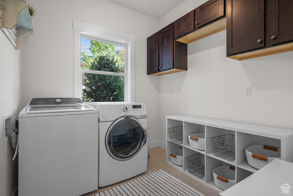 Washroom with cabinet space, separate washer and dryer, and light tile patterned floors