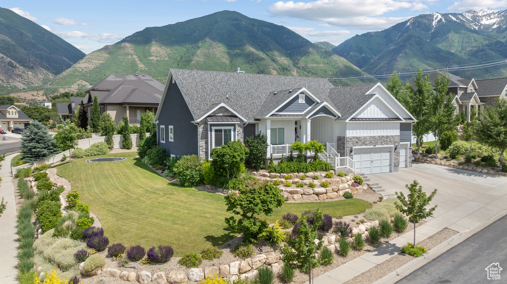 View of front of house with stone siding, board and batten siding, a garage, concrete driveway, and a front lawn