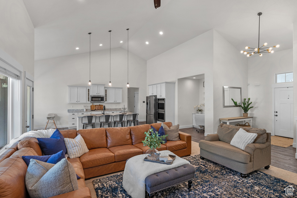 Living room with high vaulted ceiling, a chandelier, wood finished floors, recessed lighting, and healthy amount of natural light