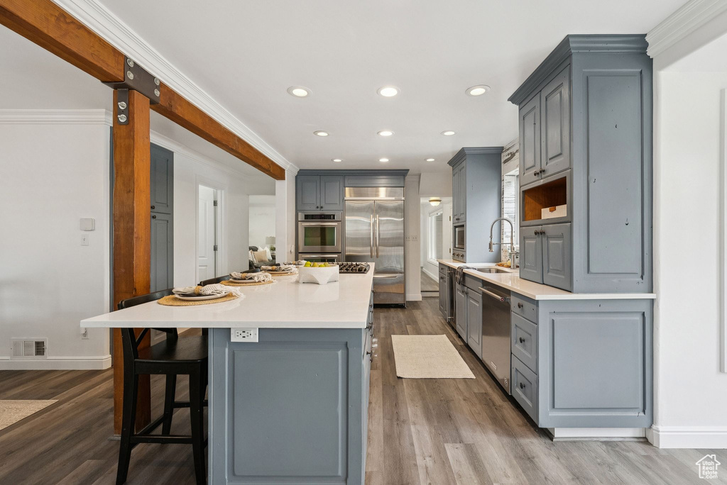 Kitchen featuring gray cabinets, appliances with stainless steel finishes, a center island, dark wood finished floors, and recessed lighting