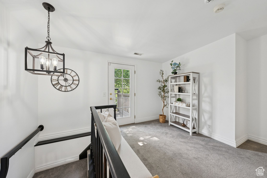 Hallway with carpet flooring, a chandelier, and an upstairs landing