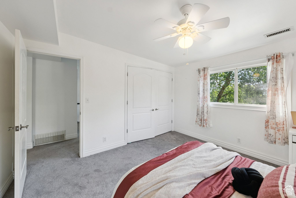 Carpeted bedroom featuring a ceiling fan and a closet