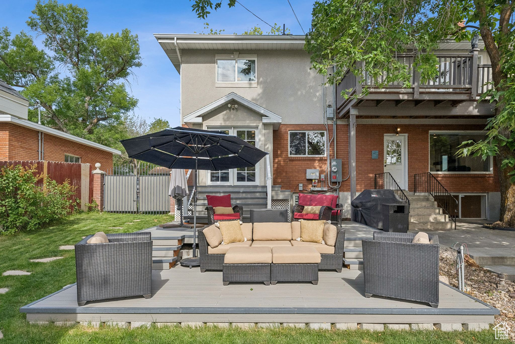 Rear view of house featuring an outdoor living space, a gate, a wooden deck, and brick siding