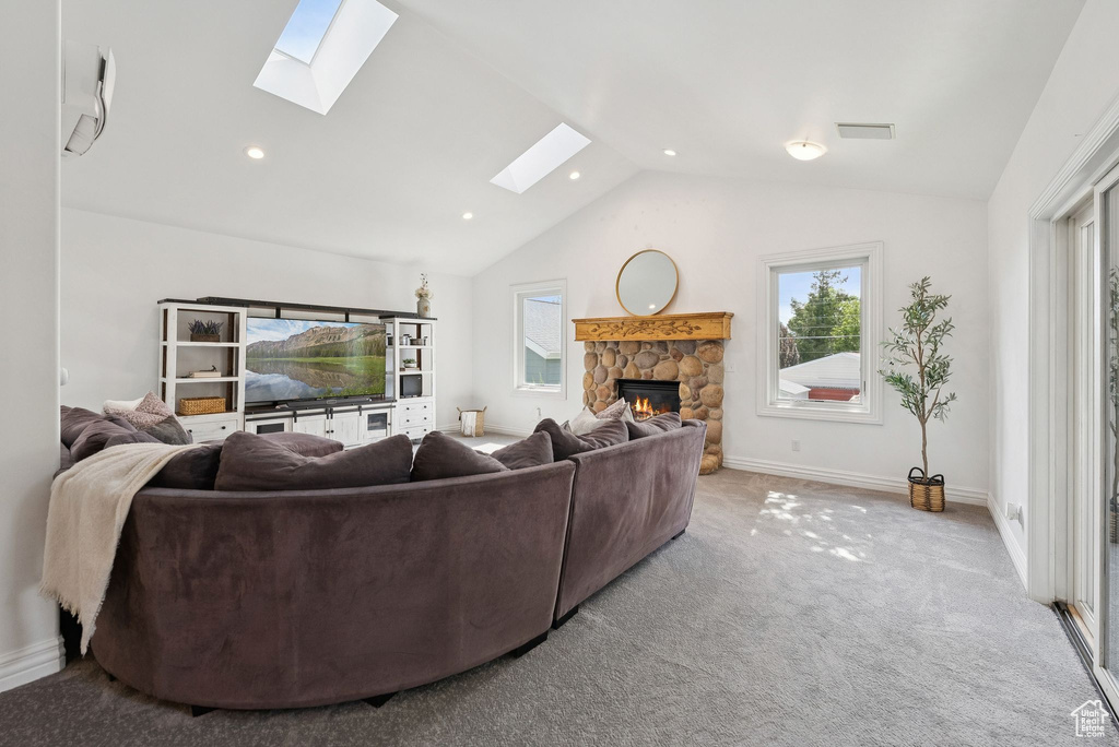 Carpeted living area with a skylight, a fireplace, vaulted ceiling, and recessed lighting