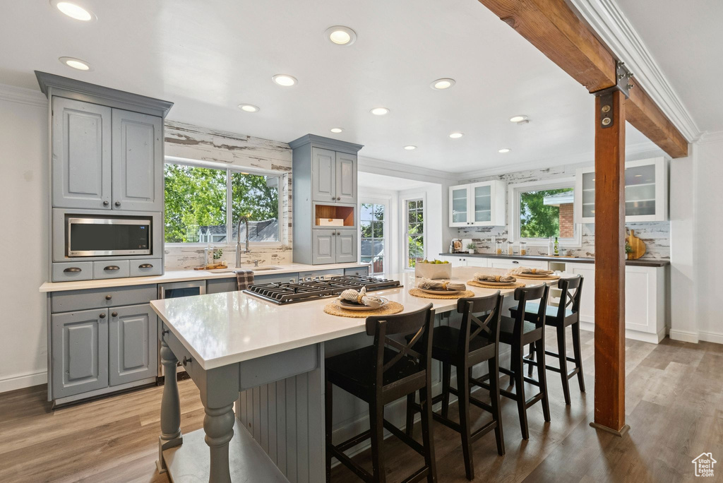 Kitchen featuring gray cabinetry, appliances with stainless steel finishes, recessed lighting, wood finished floors, and crown molding