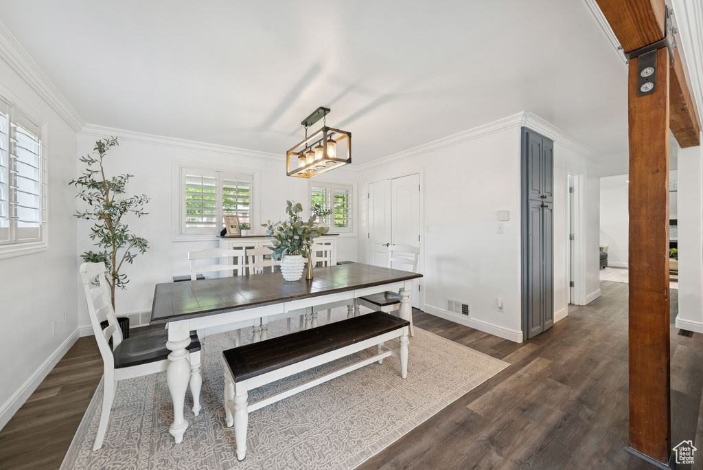 Dining area with dark wood-style flooring, a chandelier, and crown molding