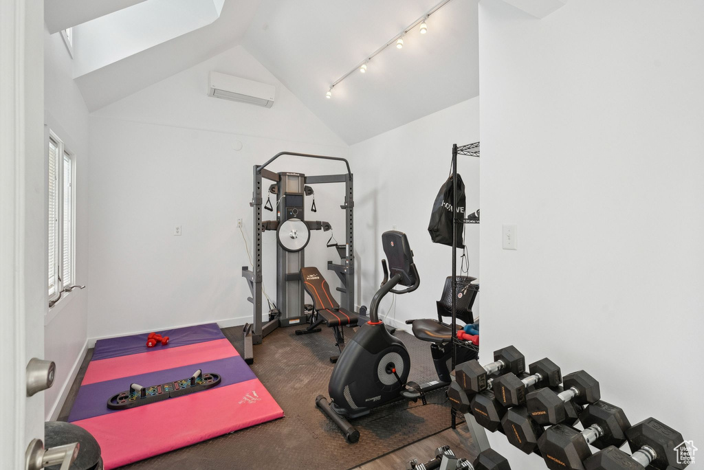 Workout area with a wall mounted AC, vaulted ceiling, and track lighting