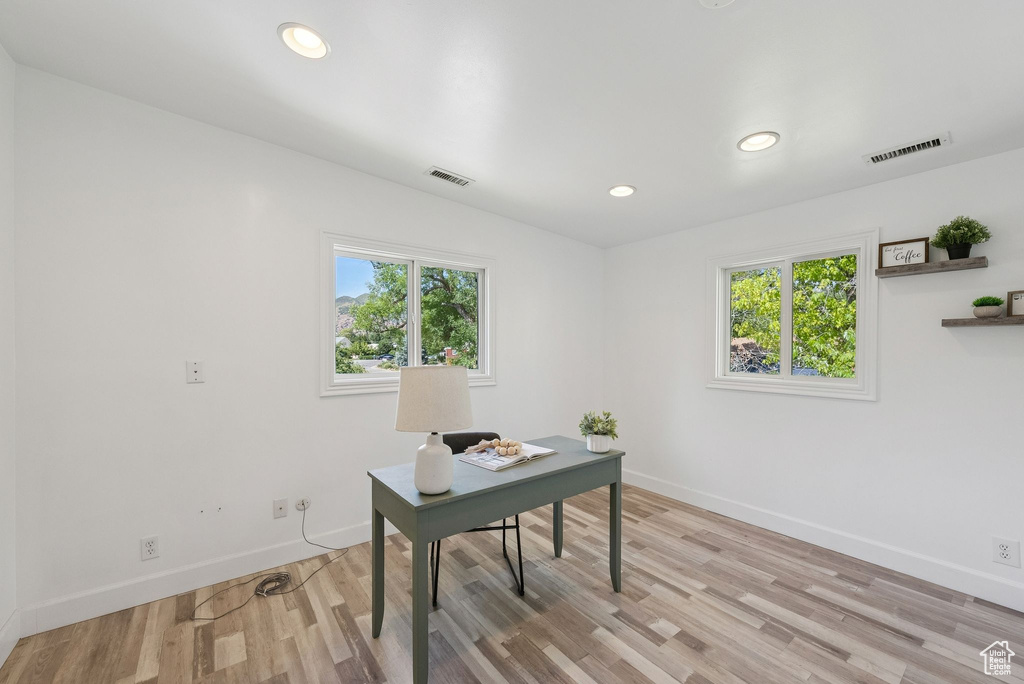 Office with light wood-style floors and recessed lighting