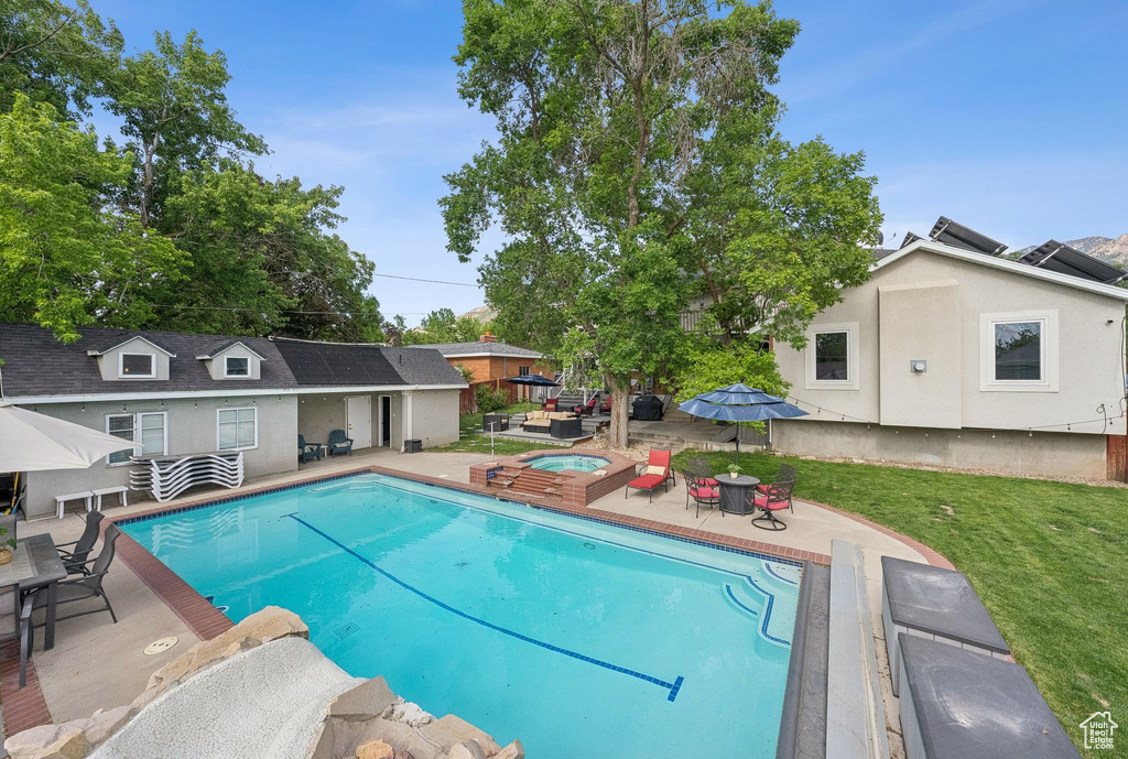 Swimming pool with an in-ground hot tub, a patio area, and a yard
