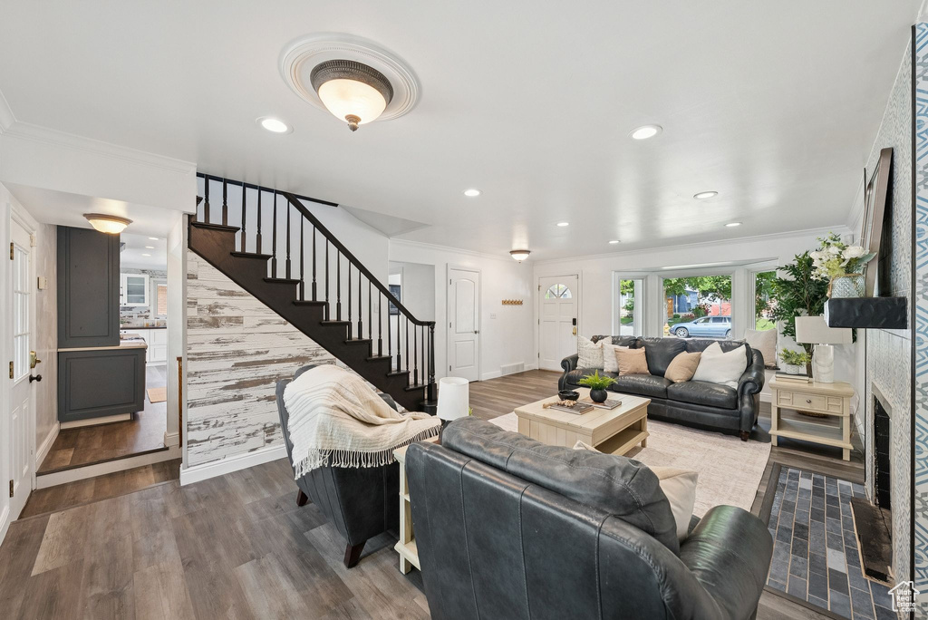 Living area with wood finished floors, stairs, ornamental molding, recessed lighting, and a glass covered fireplace