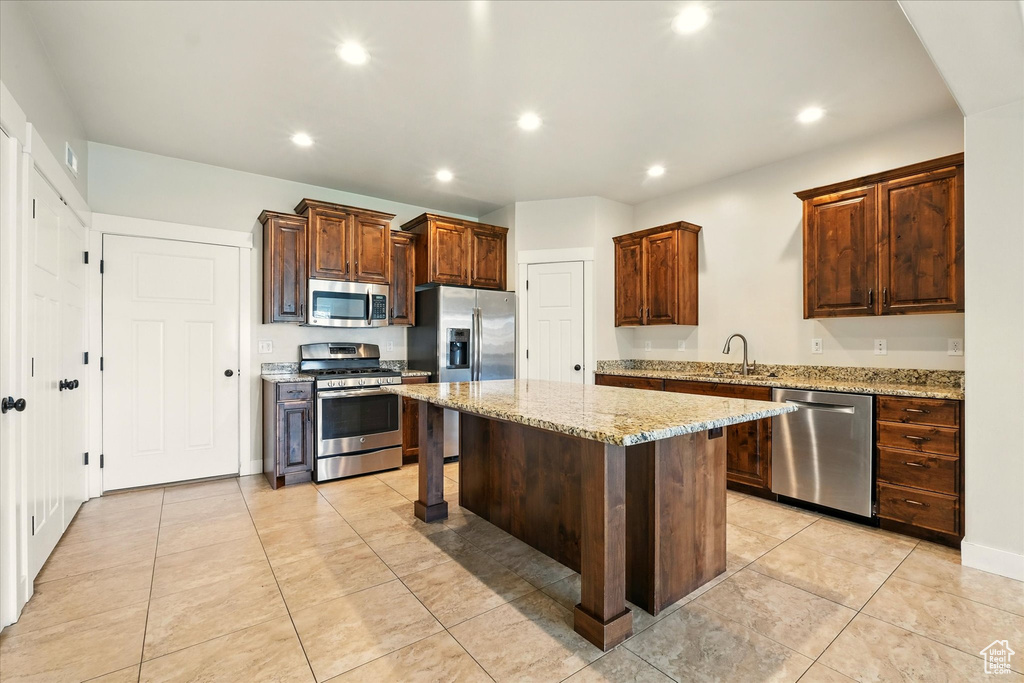 Kitchen with stainless steel appliances, a kitchen bar, recessed lighting, a center island, and light tile patterned flooring