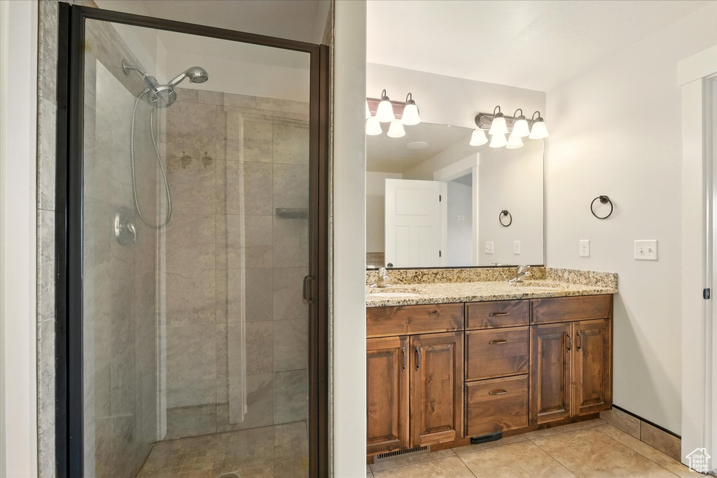 Bathroom featuring a shower stall, double vanity, and tile patterned floors