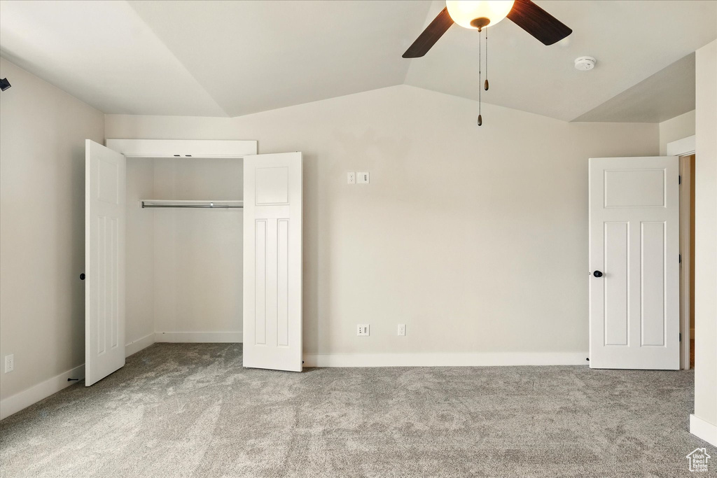 Unfurnished bedroom featuring carpet, a closet, vaulted ceiling, and a ceiling fan
