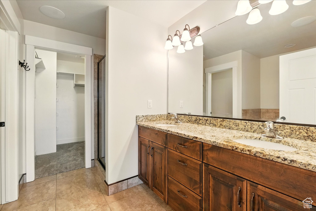 Bathroom with double vanity, a shower stall, tile patterned floors, and a walk in closet