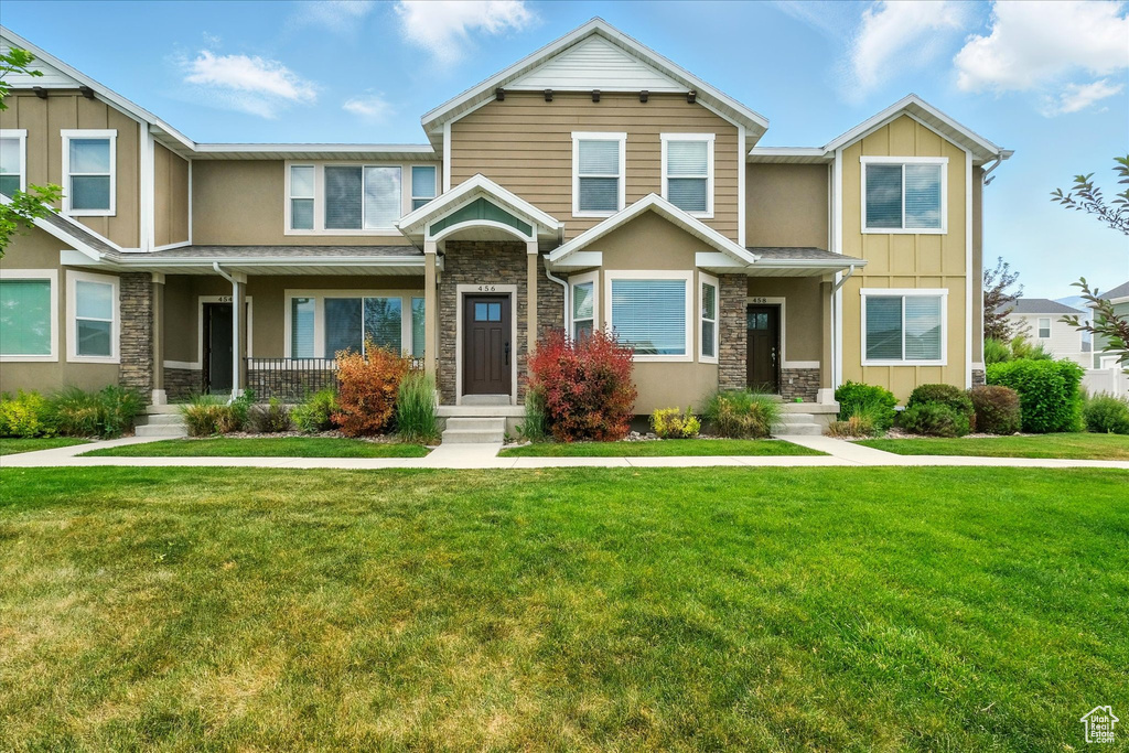 Townhome / multi-family property with stone siding and a front yard