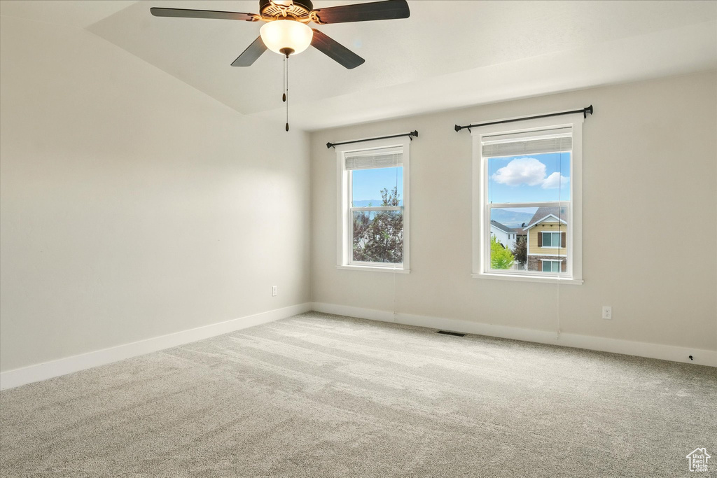 Carpeted spare room featuring lofted ceiling and ceiling fan