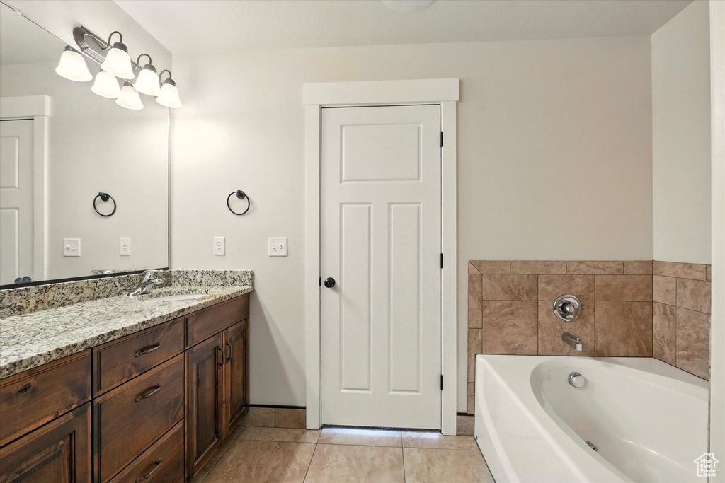 Bathroom featuring vanity, a garden tub, and tile patterned flooring
