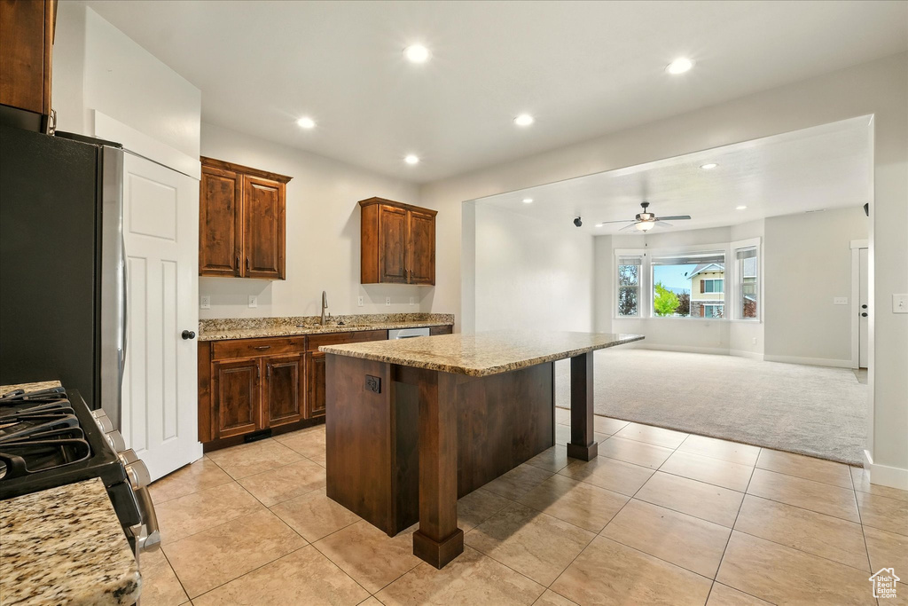 Kitchen featuring light colored carpet, a kitchen island, recessed lighting, gas range, and light stone counters