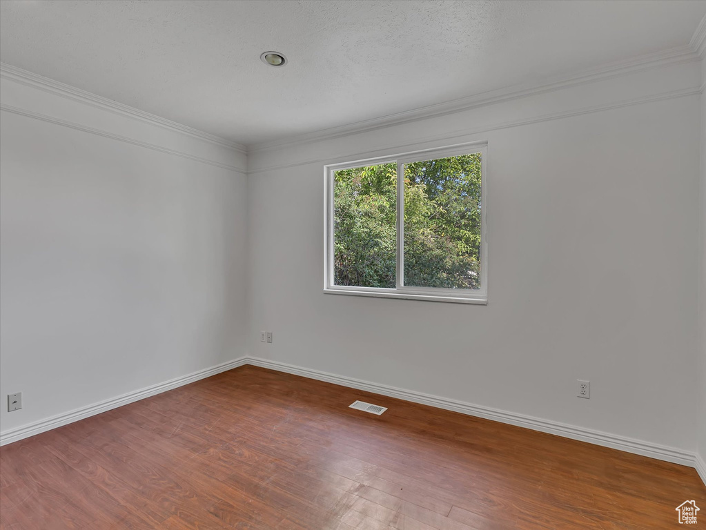 Unfurnished room featuring wood finished floors and ornamental molding