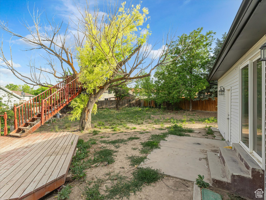 Fenced backyard featuring a wooden deck, stairs, and a patio area