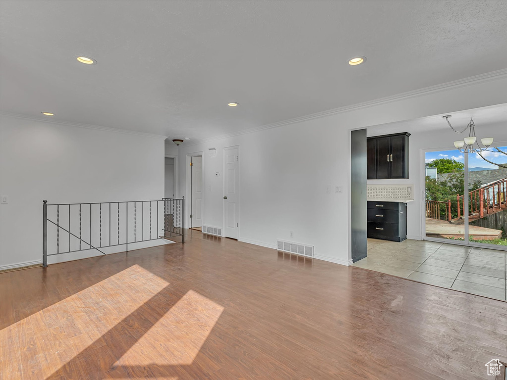 Unfurnished room with light wood-style flooring, ornamental molding, a chandelier, recessed lighting, and a fireplace