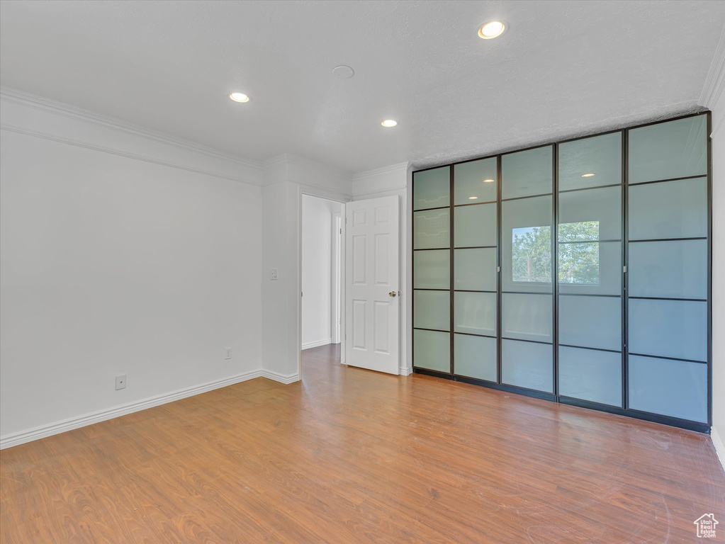 Unfurnished room featuring recessed lighting, wood finished floors, and ornamental molding