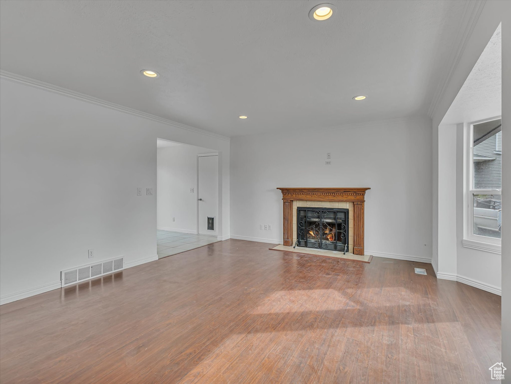Unfurnished living room with a fireplace with flush hearth, ornamental molding, wood finished floors, and recessed lighting