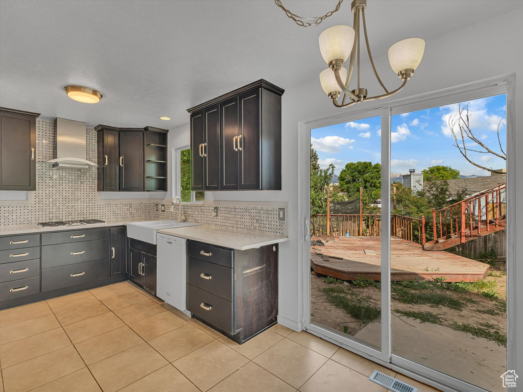 Kitchen with wall chimney range hood, white appliances, light tile patterned flooring, and light countertops
