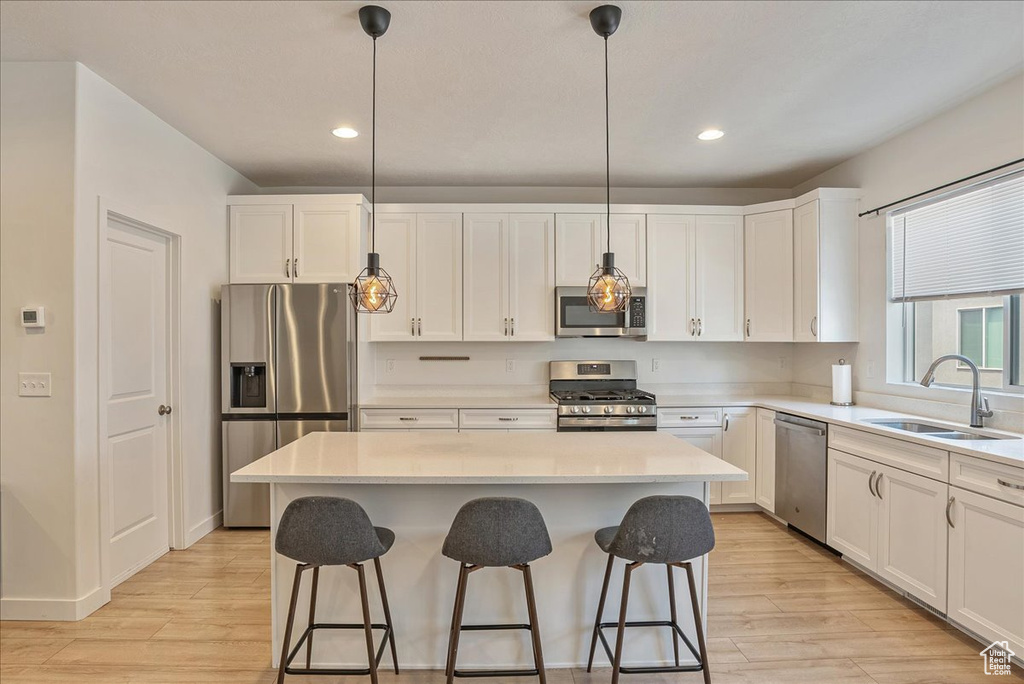 Kitchen with appliances with stainless steel finishes, light wood finished floors, white cabinetry, and recessed lighting